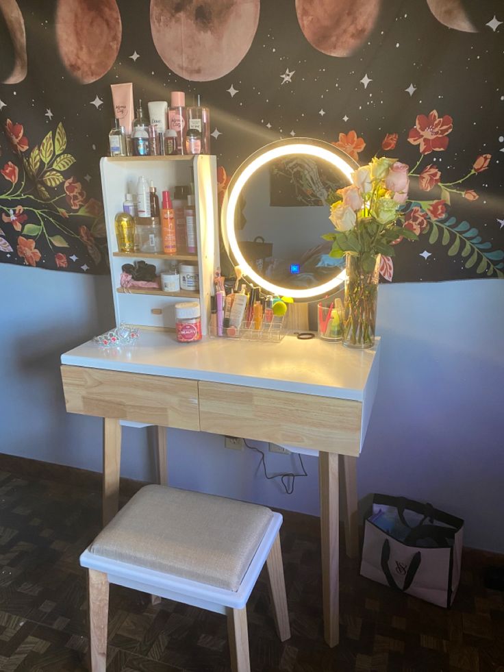 a vanity with a mirror, stool and flowers on it in front of a space themed wall