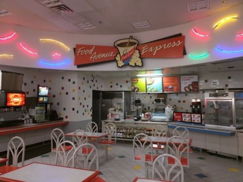 the inside of a fast food restaurant with neon lights on the ceiling and tables set up for diners