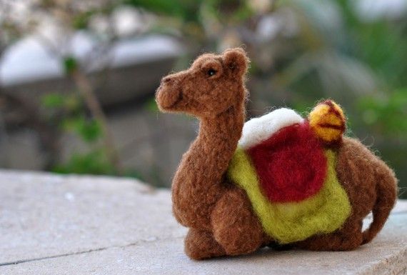 a small stuffed camel sitting on top of a stone wall