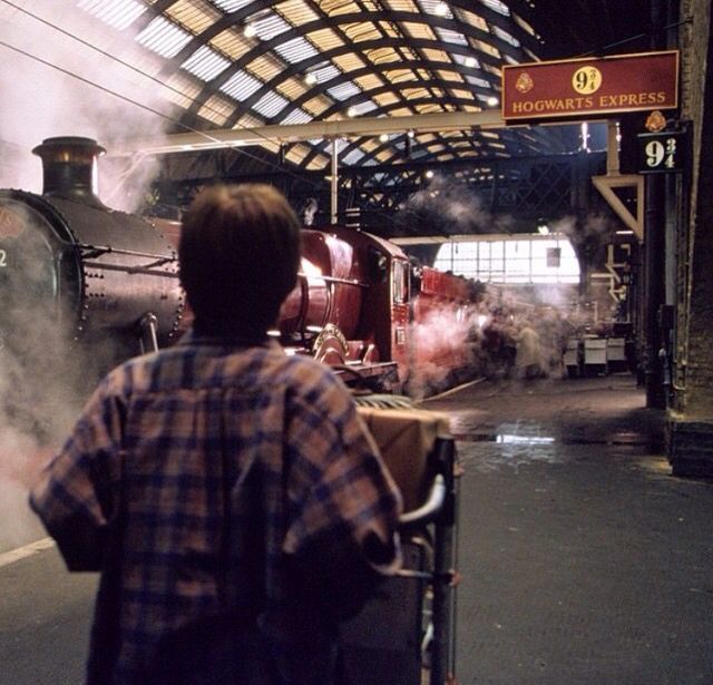 a man standing next to a train at a station with steam pouring out of it