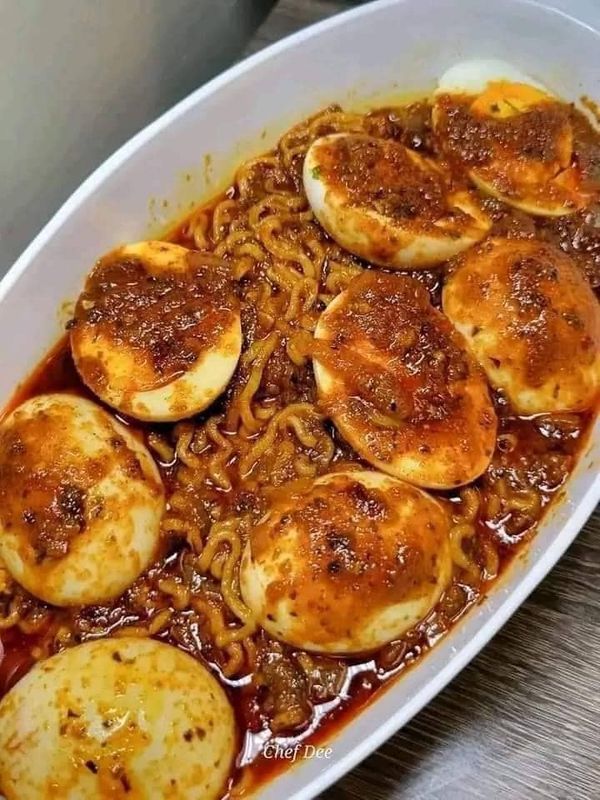 a large white dish filled with noodles and dumplings in sauce on top of a wooden table