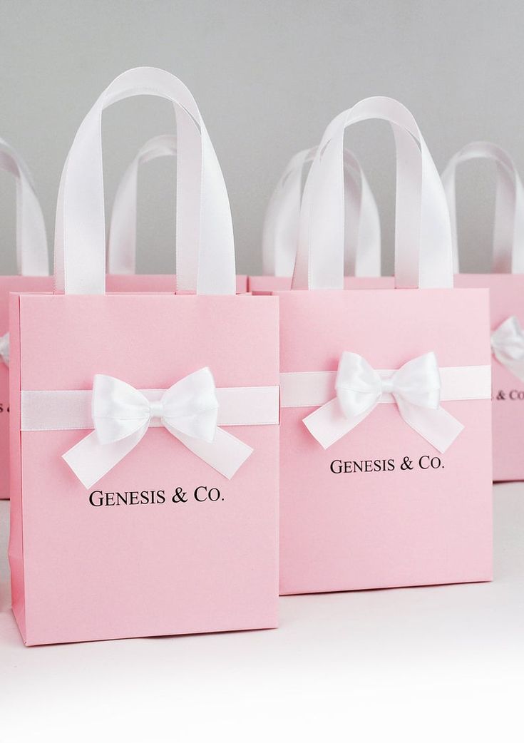 four pink bags with white bows on them