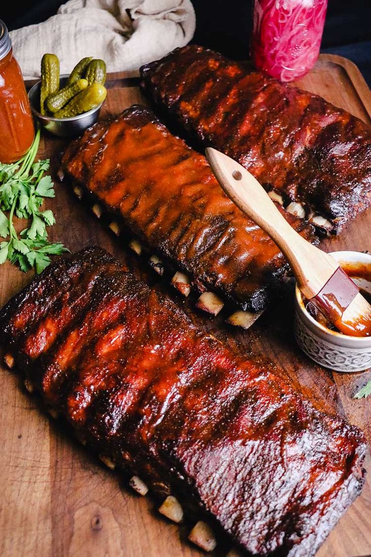 bbq ribs on a cutting board with pickles and sauce