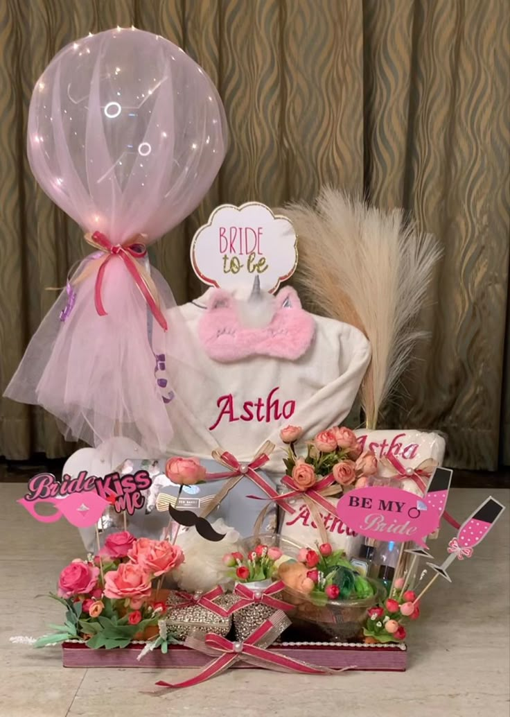 a basket filled with balloons and flowers on top of a table next to other items