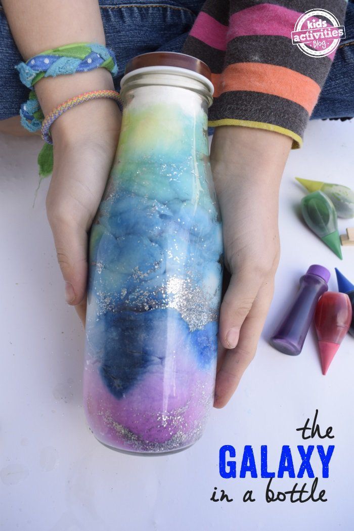 a person is holding a glass bottle with glitter on it and the words, the galaxy in a bottle