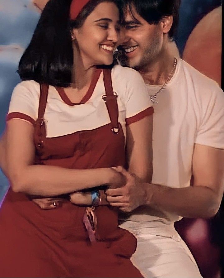 a man and woman sitting next to each other in front of a wall with an advertisement on it