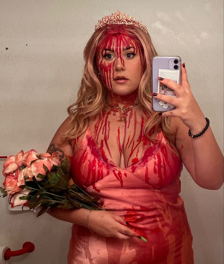 a woman dressed in red holding flowers and taking a selfie with her cell phone