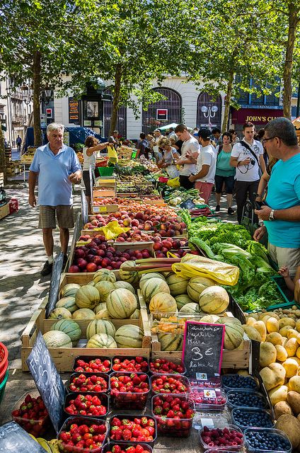 people shopping at an outdoor market with fruits and vegetables