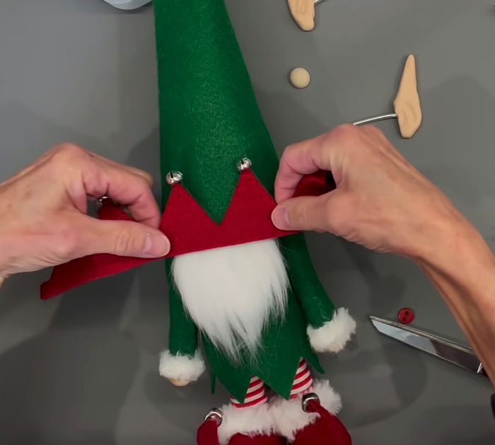 two hands are working on an elf's hat