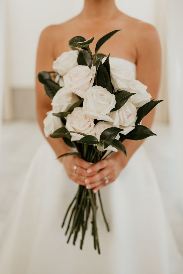 a woman holding a bouquet of white roses