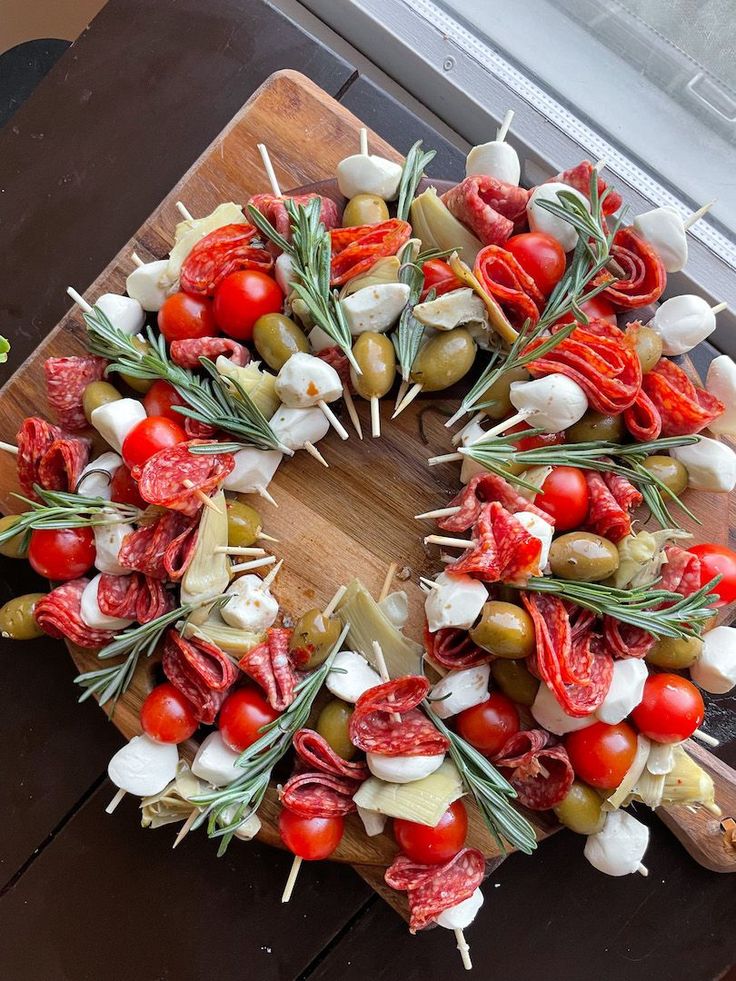 a wreath made out of vegetables and meats on a cutting board next to a window