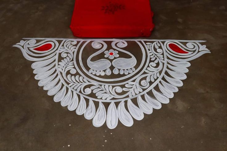 an intricately designed piece of art on the ground next to a red object with white paint