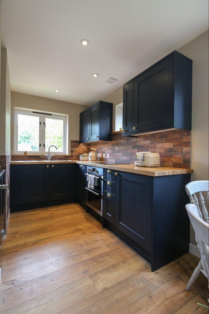 a kitchen with black cabinets and wood flooring is pictured in this image from the inside