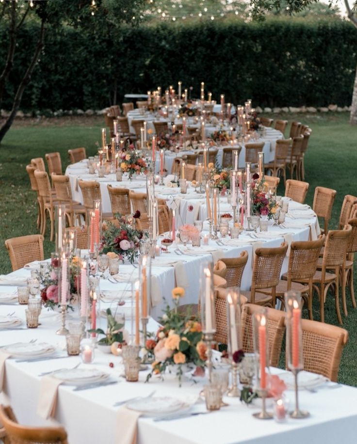 a long table is set with candles and flowers for an outdoor wedding reception in the backyard