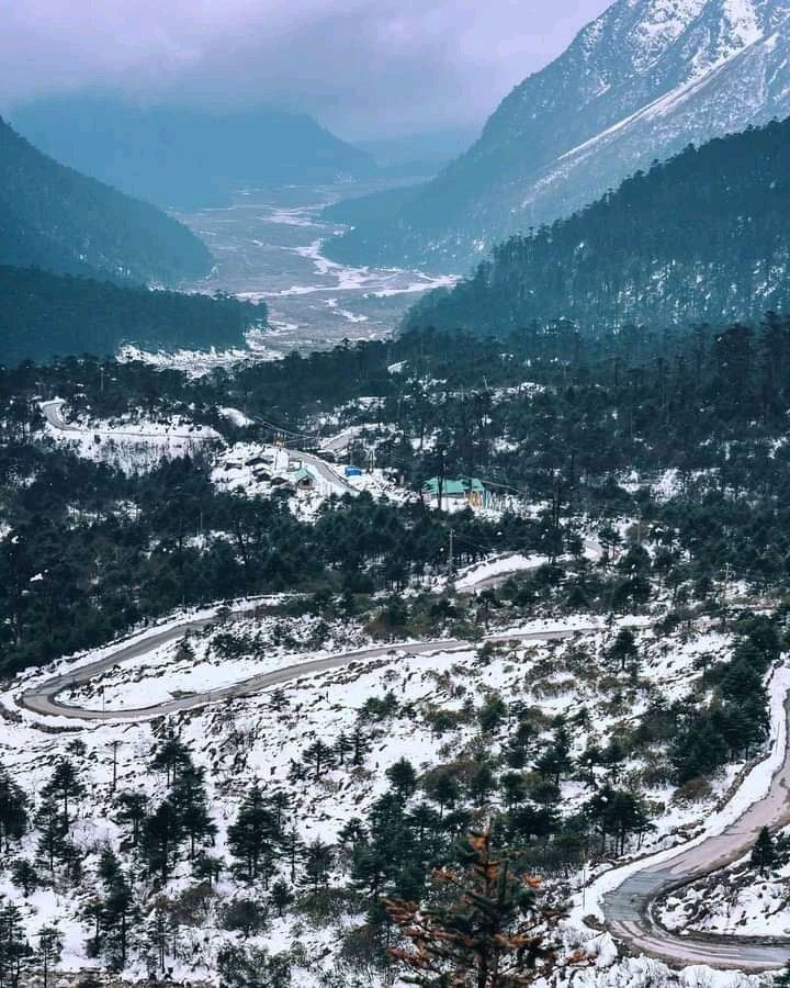 snow covered mountains and roads are seen in this aerial view from the top of a hill