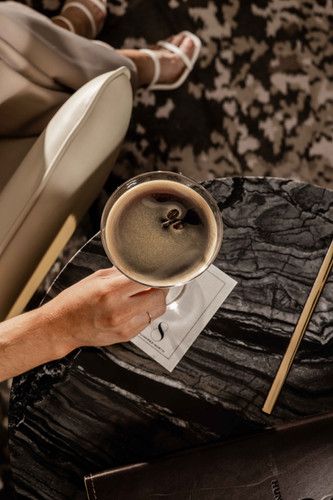 a person sitting on a couch holding a coffee cup in front of their foot rest