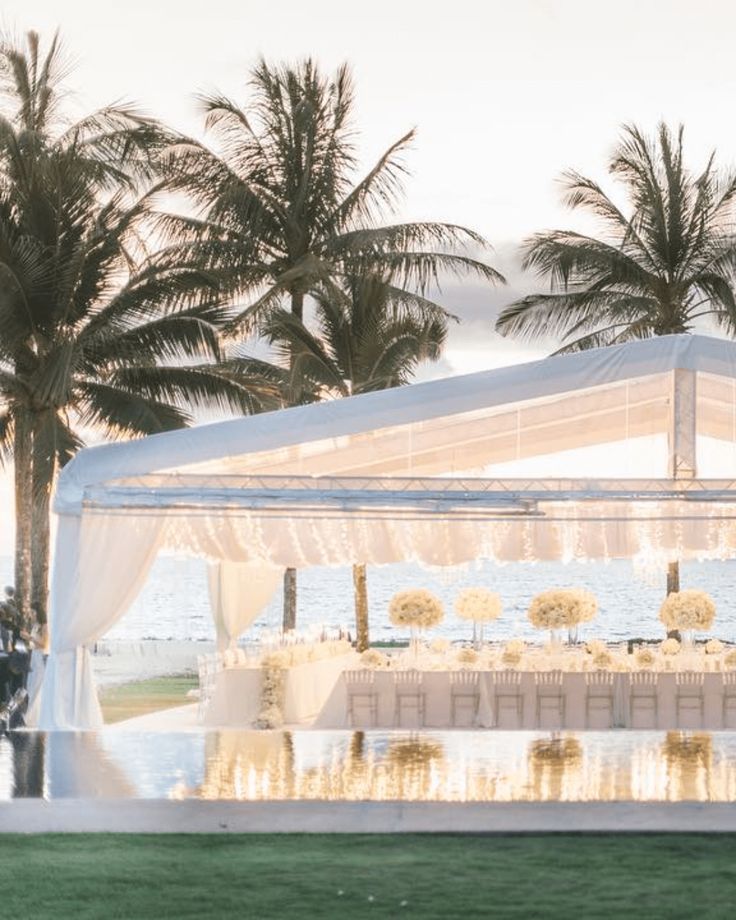 an outdoor wedding setup with white linens and palm trees