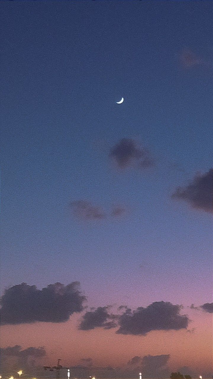 an airplane is flying in the sky at night with clouds and lights behind it as the sun sets