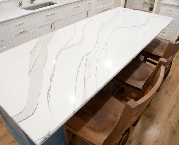 a kitchen island with marble top and wooden chairs