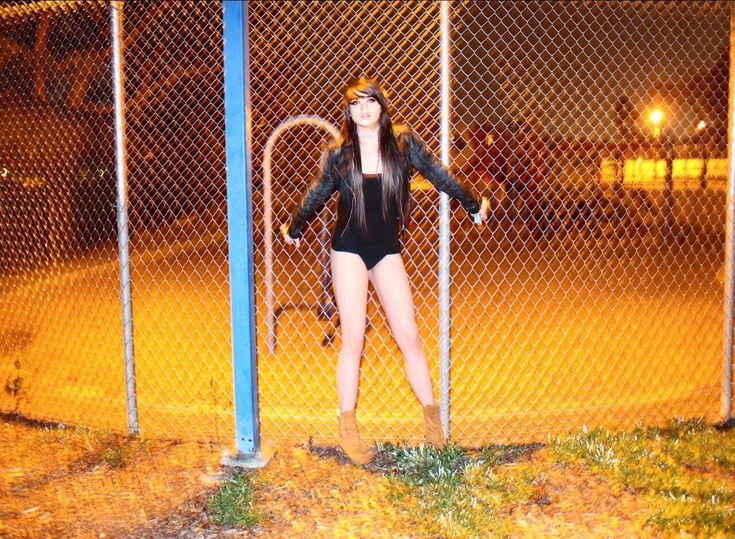 a woman standing behind a chain link fence