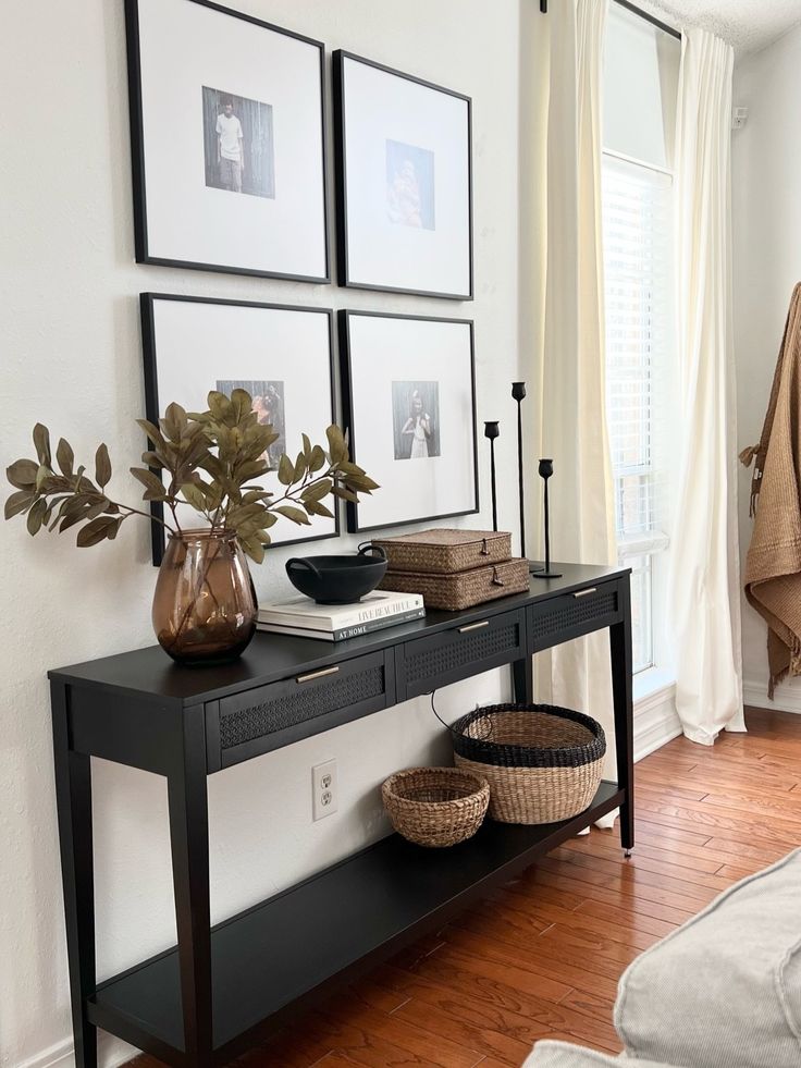 a living room with pictures on the wall and a black table in front of it