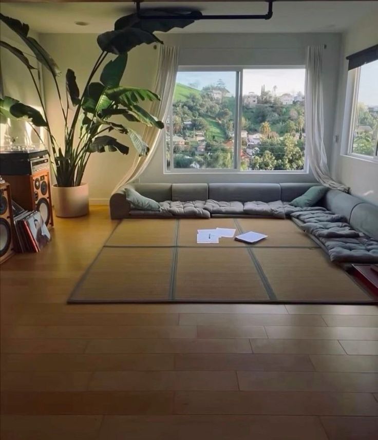 a living room with a large window, couch and rug on the floor in front of it