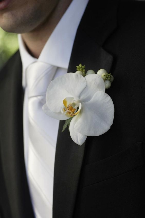 a man in a tuxedo with a white flower on his lapel pin