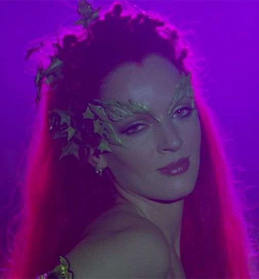 a woman with long red hair and flowers on her head is posing for the camera