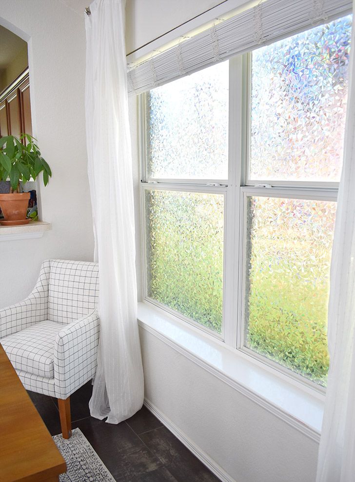 a white chair sitting in front of a window next to a wooden table and potted plant