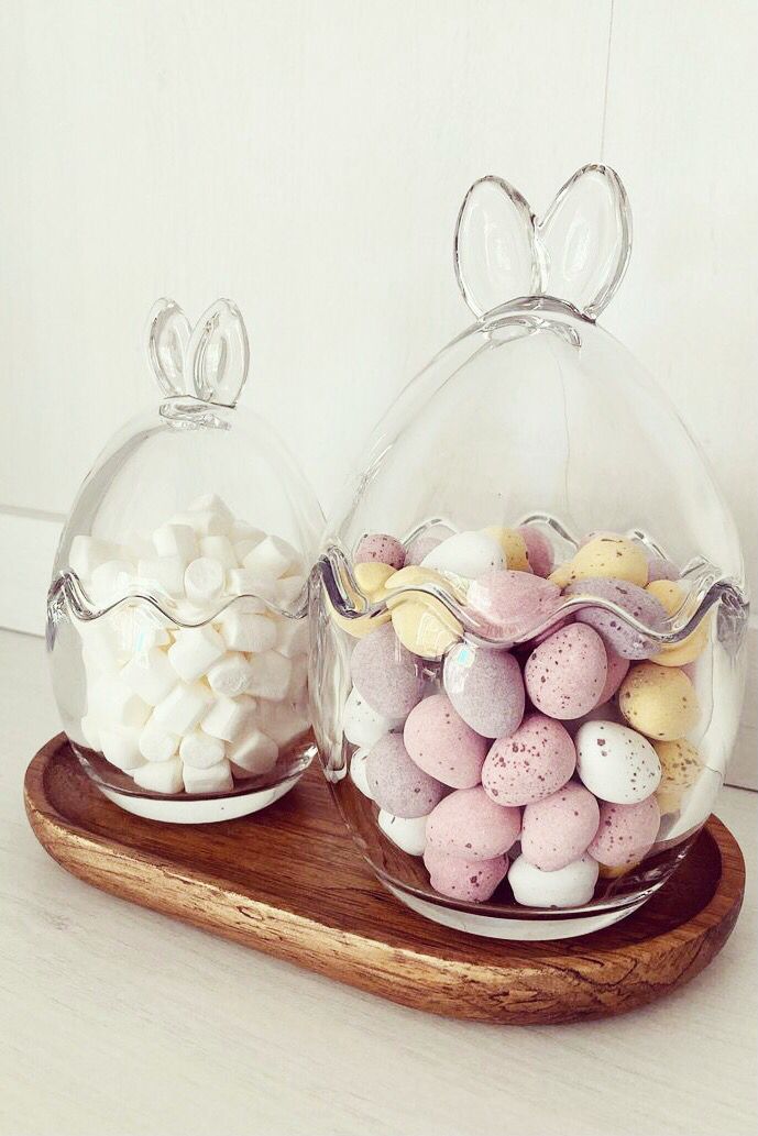 two glass domes filled with candy and marshmallows on a wooden platter