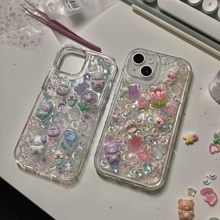 two clear cases sitting on top of a table next to a keyboard and phone case