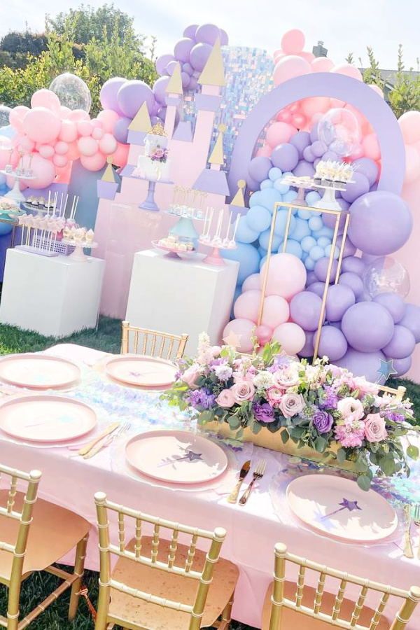 a table set up for a princess birthday party with balloons and flowers on it,