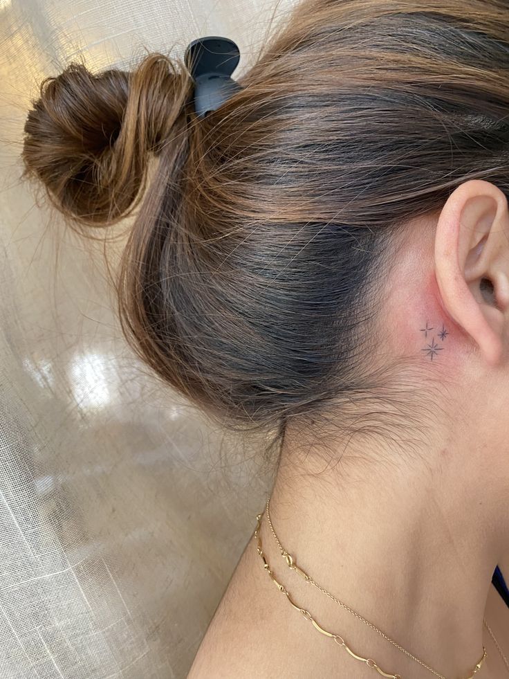 a woman with a small star tattoo on her left side of her neck and behind her ear