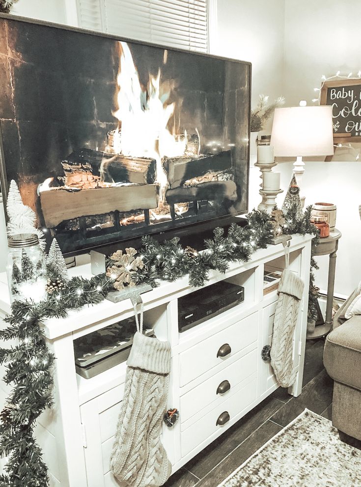 a living room decorated for christmas with stockings and garlands on the fireplace mantel