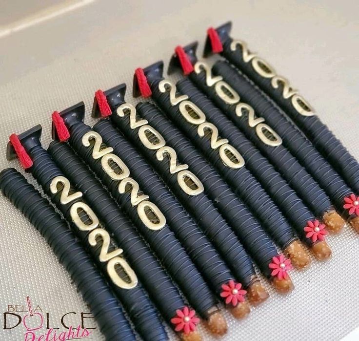 a bunch of black and gold hair clips with red flowers on each end, sitting on a white surface