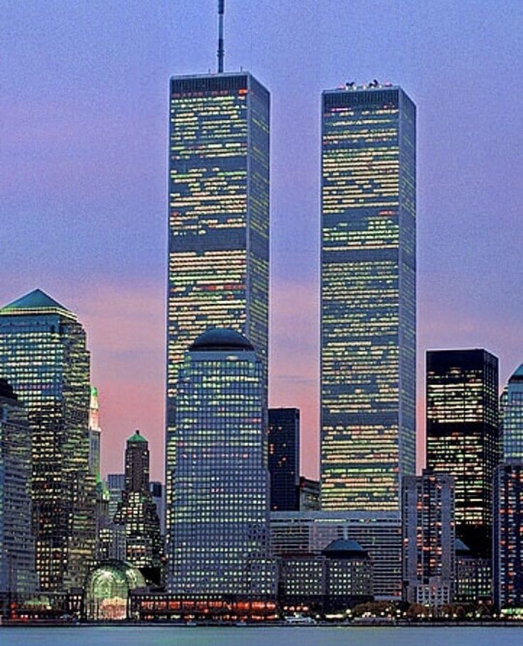 the city skyline is lit up at night, with skyscrapers in the foreground