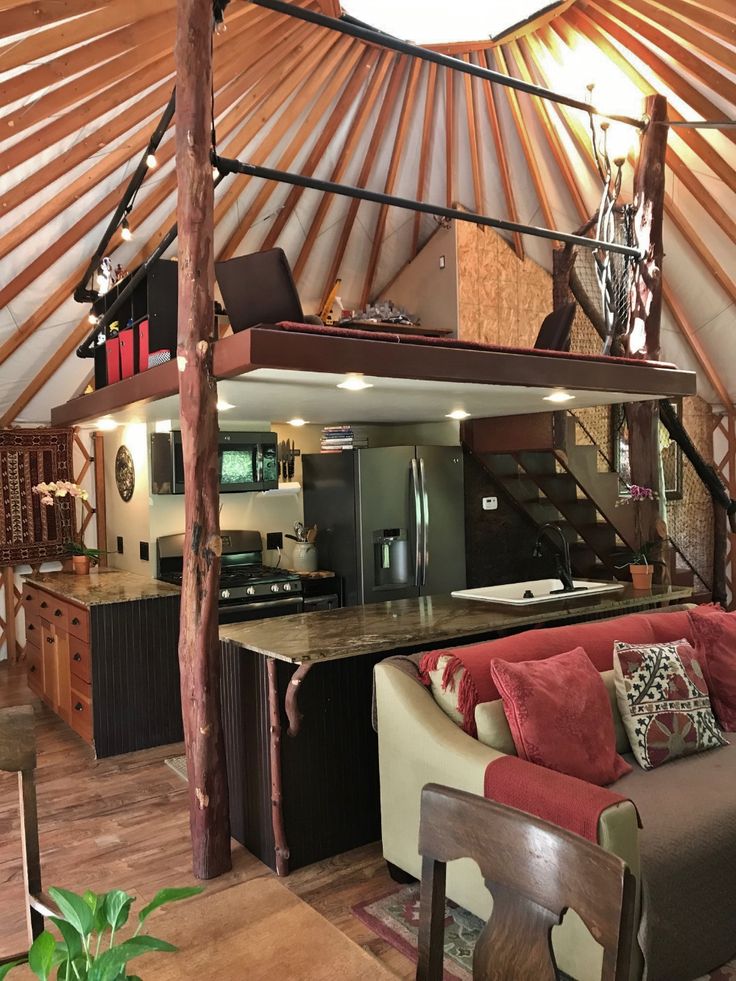 the inside of a yurt with couches, tables and stairs leading up to it