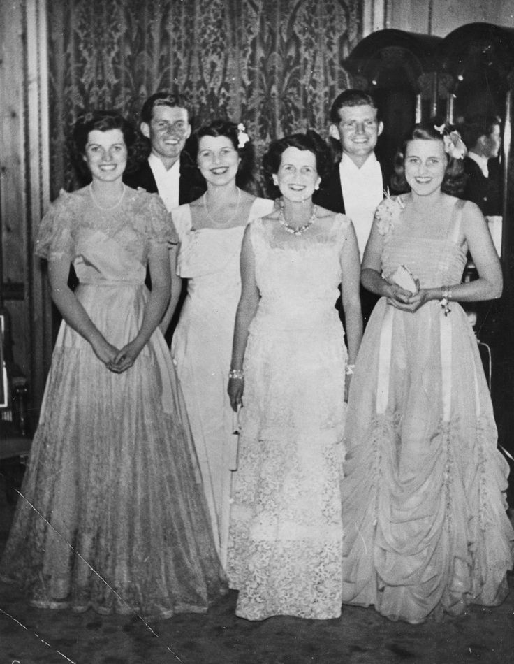 an old black and white photo of some people in formal dress posing for the camera