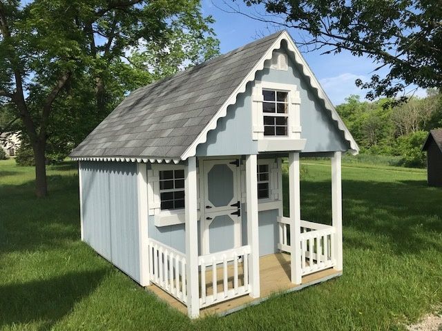 a small white wooden house in the grass