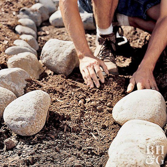 a man kneeling down to pick up rocks from the ground with his hands on them