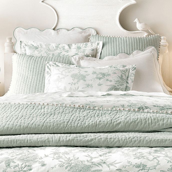 a white bed topped with lots of pillows next to a night stand and nightstands