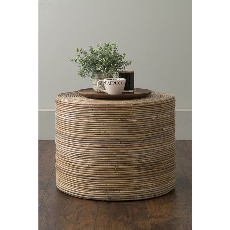 a coffee table with a plant on top and a mug sitting on it's side