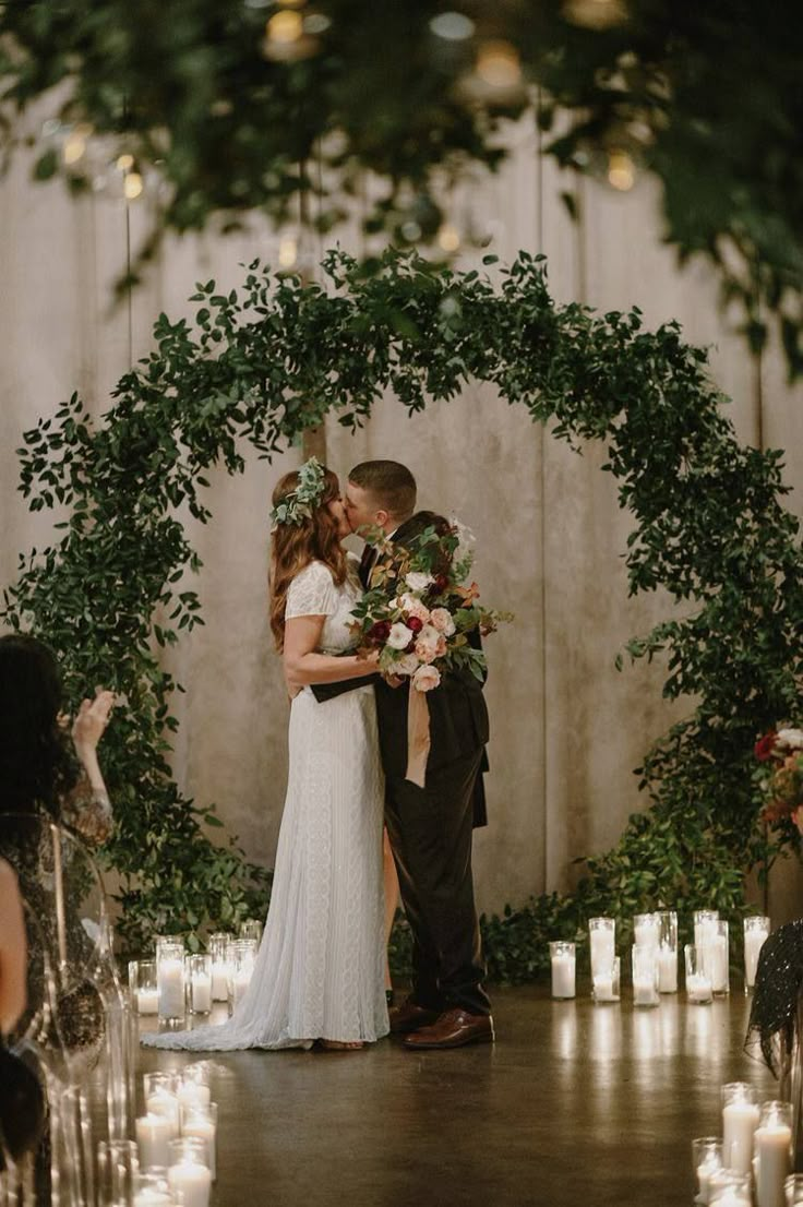 a bride and groom kissing in front of candles