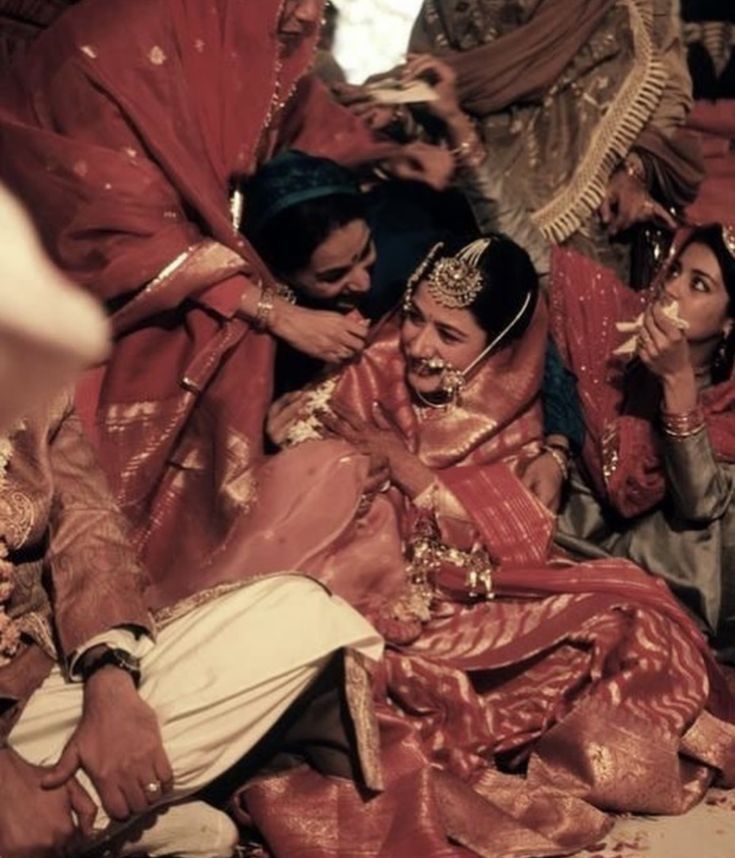 a group of people sitting around each other on the ground with one woman in red dress