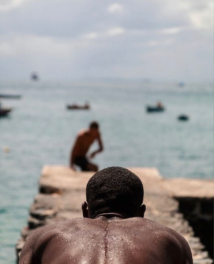 a man sitting on a dock looking out at the ocean