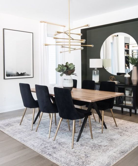 a dining room table with black chairs and a large mirror on the wall behind it