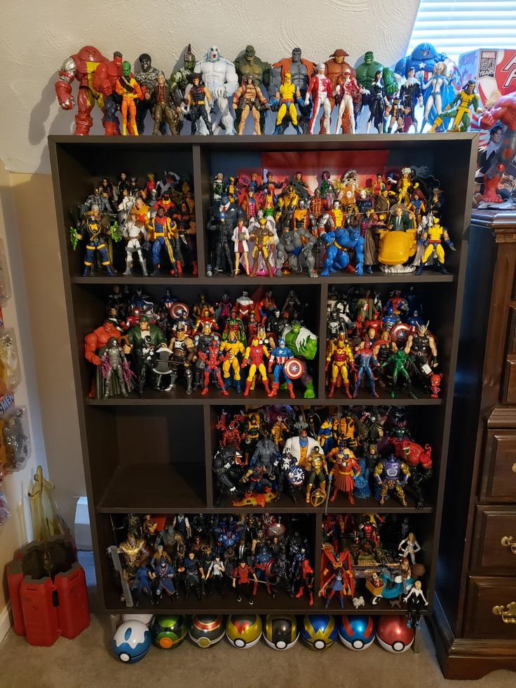 a book shelf filled with lots of action figures next to a dresser full of toys