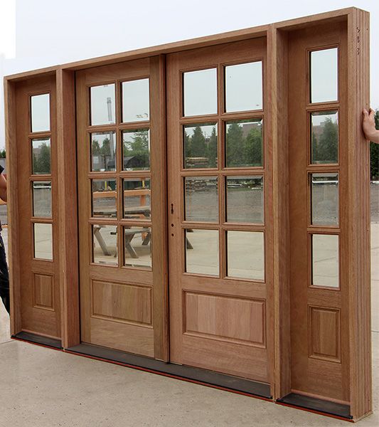 a man standing next to two doors with windows on each side and one door open