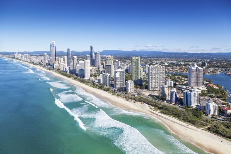 an aerial view of surfers in the ocean and cityscape with high rise buildings