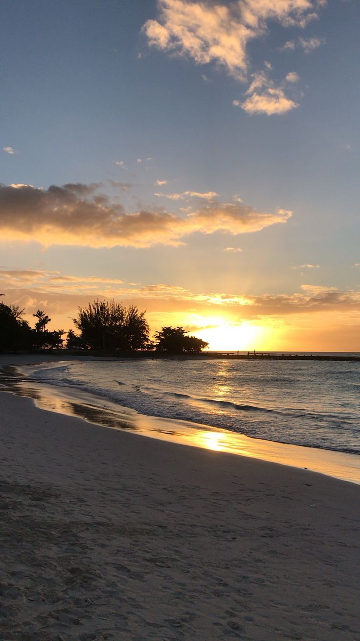 the sun is setting over the ocean on the beach